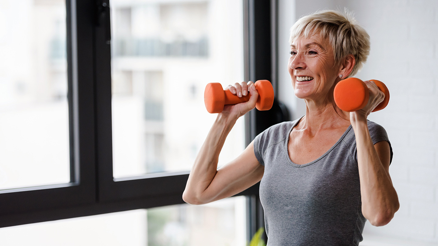 Older woman lifts small orange weights